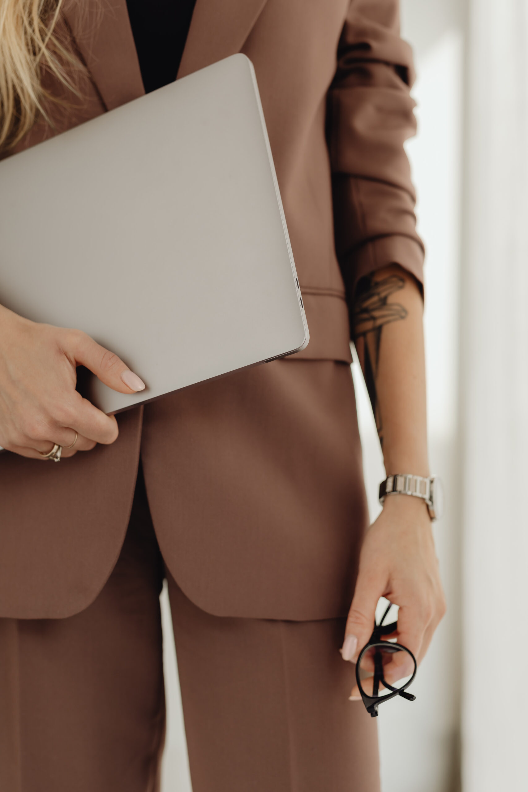Elegant businesswoman in Mocha Mousse colored suit with laptop